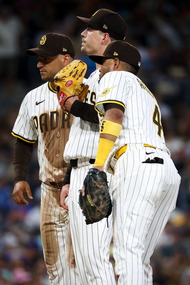 Ryan Bergert #38 of the San Diego Padres, center, flanked by teammates Jose Iglesias #7 and Luis Arraez #4, reacts before being pulled from the game against the New York Mets during the fifth inning at Petco Park on Tuesday, July 29, 2025 in San Diego, CA. (Meg McLaughlin / The San Diego Union-Tribune)