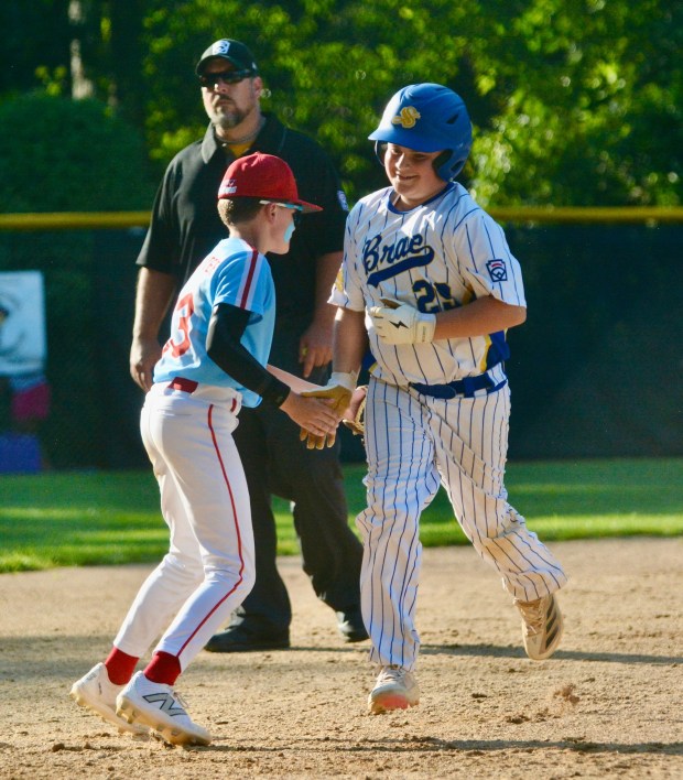 Sunnybrae's Declan Sweeney, right, slaps hands with Nottingham third baseman Owen McWhorter, left, as he rounds the bases after hitting a solo home run in the fifth inning during the District 12 Little League Baseball championship round on Saturday evening at Ed Nevius Field in Hamilton Twp. (Kyle Franko/ Trentonian Photo)