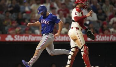 Texas Rangers' Wyatt Langford, left, scores on a single by Evan Carter as Los Angeles Angels catcher Logan O'Hoppe stands by during the eighth inning of a baseball game Wednesday, July 30, 2025, in Anaheim, Calif. (AP Photo/Mark J. Terrill)