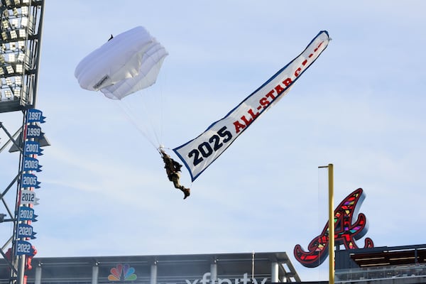 A parachute flier enters Truist Park during the ceremonies for unveiling the All-Star Game logo in Atlanta. (Miguel Martinez/AJC 2024)