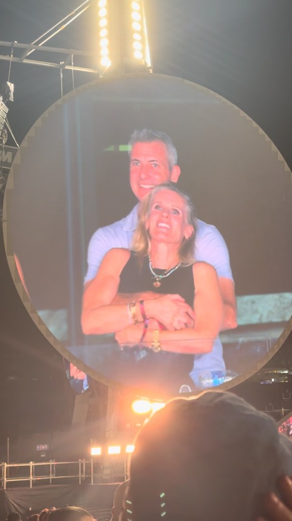 Couple shown on a large screen at a Coldplay concert.