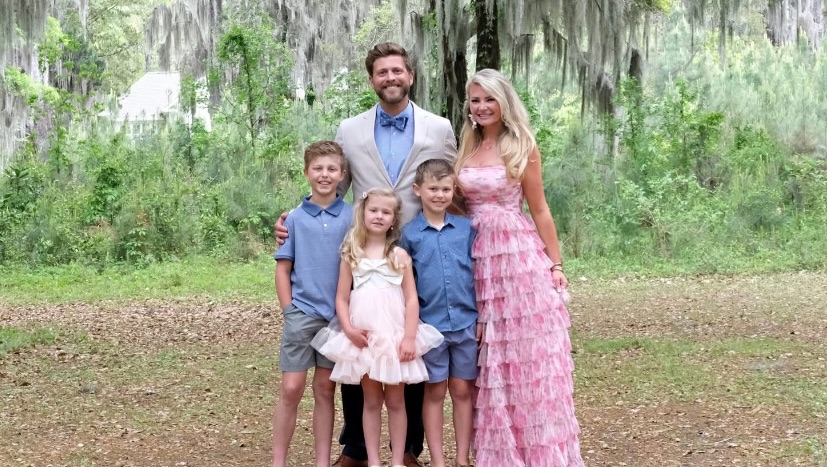 Family portrait of two adults and three children in a park.