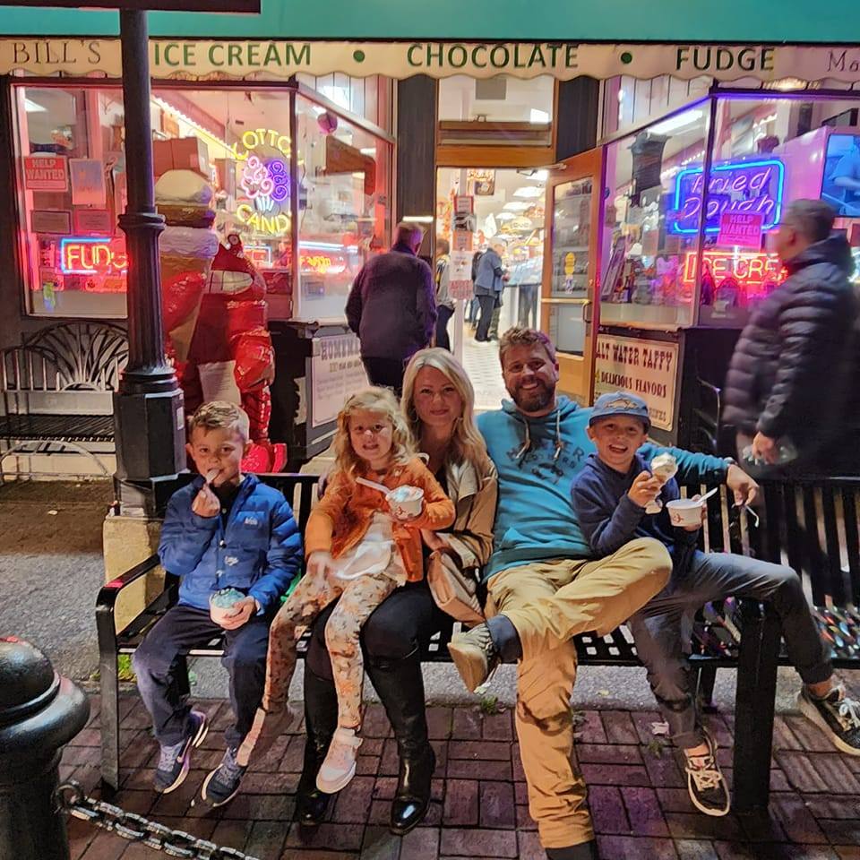 Family eating ice cream outside a shop.