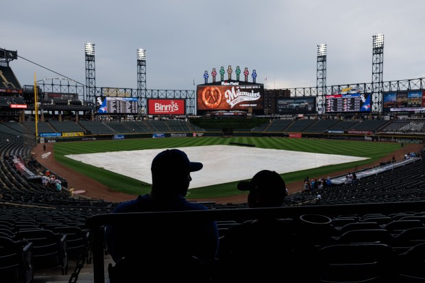 Fans sit in their seats as the rain tarp sits on the field before the Chicago White Sox play the Toronto Blue Jays at Rate Field Tuesday July 8, 2025, in Chicago. (Armando L. Sanchez/Chicago Tribune)