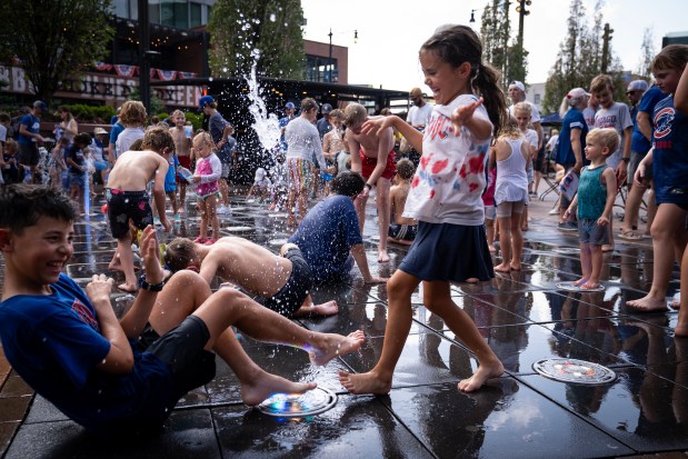 Jonah and Lucy Puentes from California play in the fountains at Gallagher Way during the heat advisory at Wrigley Field, July 23, 2025. (E. Jason Wambsgans/Chicago Tribune)