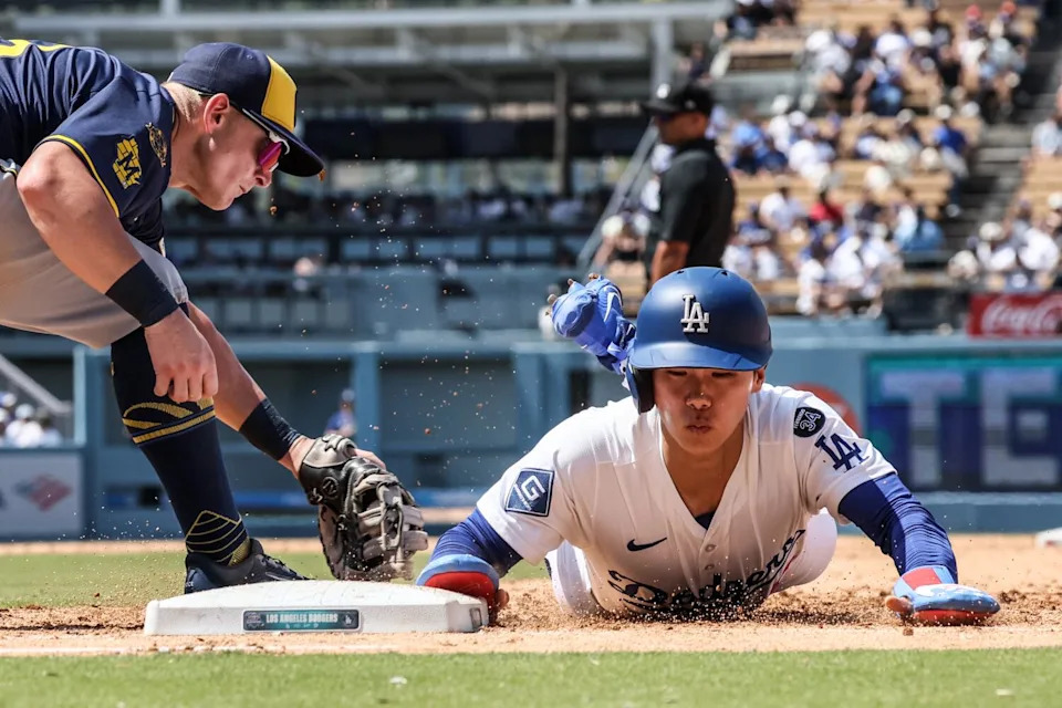 Hyeseong Kim slides safely into first, beating the tag of Milwaukee Brewers first baseman Andrew Vaughn.
