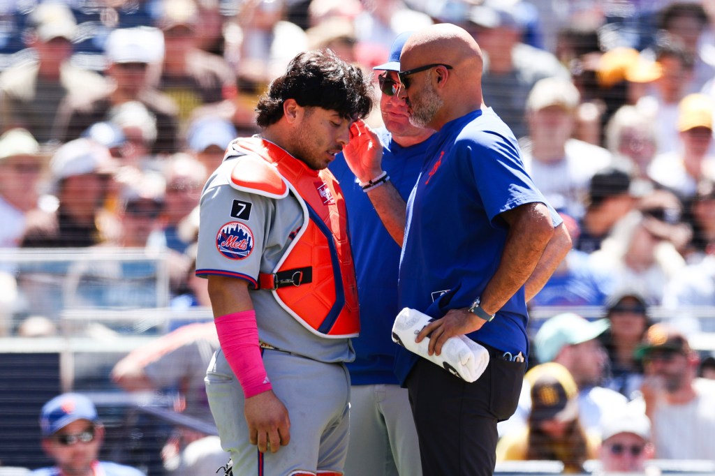 New York Mets catcher Francisco Alvarez is attended to by a trainer after being hit by a foul ball.