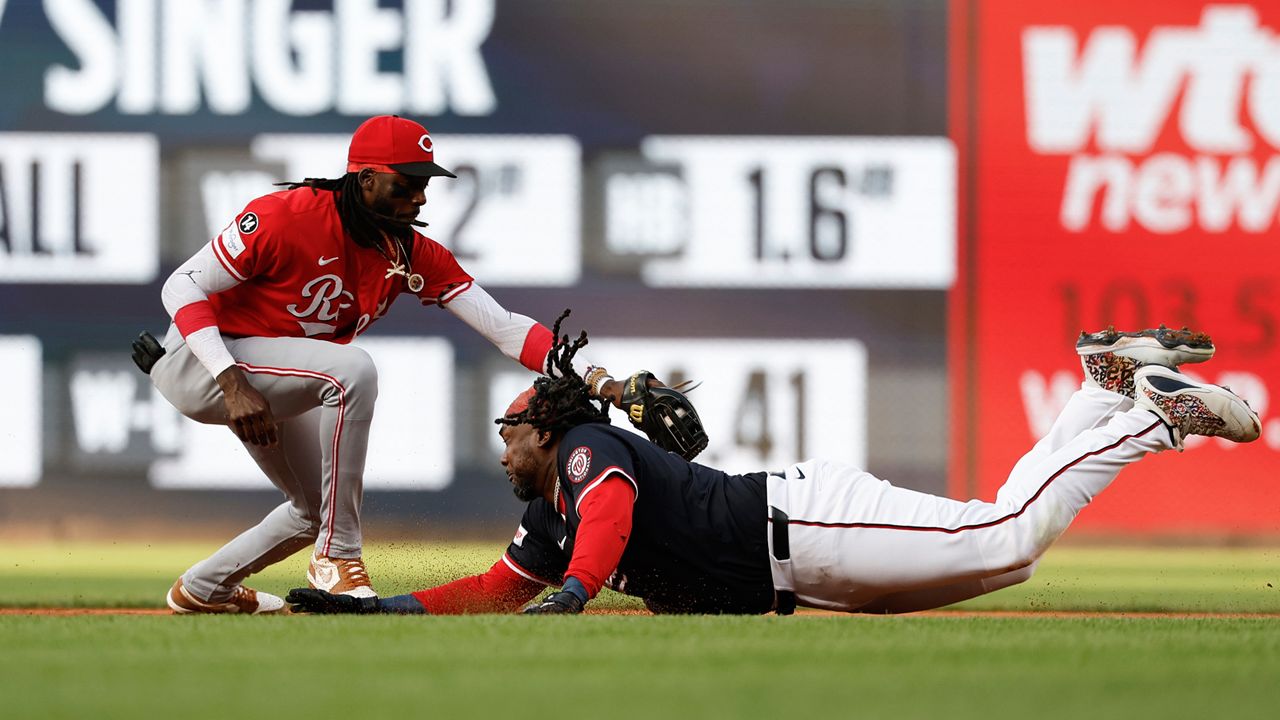 Washington Nationals' Josh Bell, right, avoids a tag by Cincinnati Reds shortstop Elly De La Cruz, left, and slides into second base on a double hit off pitcher Brady Singer during the first inning of a baseball game in Washington, Monday, July 21, 2025. (AP Photo/Terrance Williams)