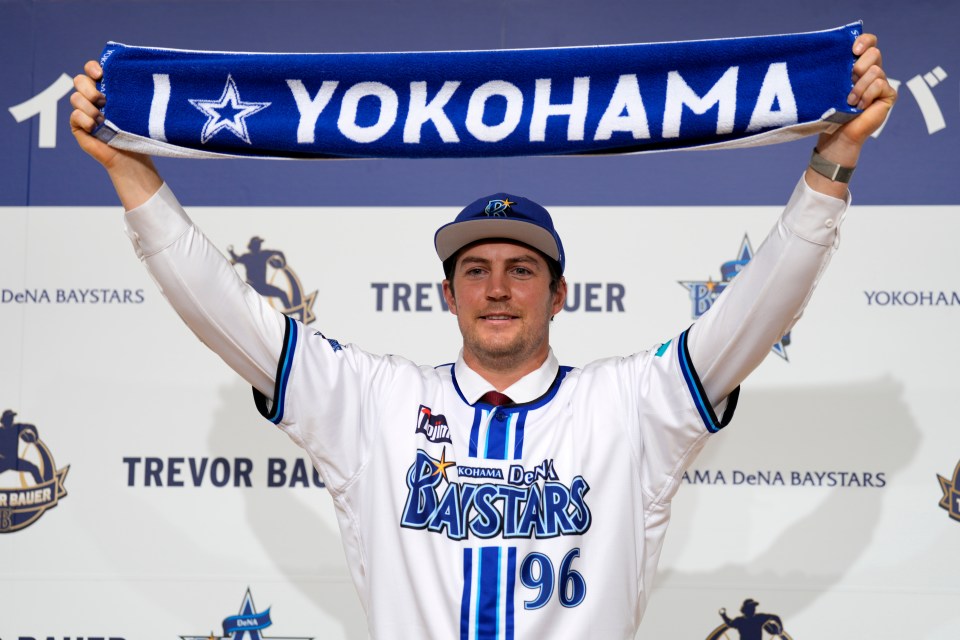Trevor Bauer in Yokohama DeNA BayStars uniform holding a team scarf.