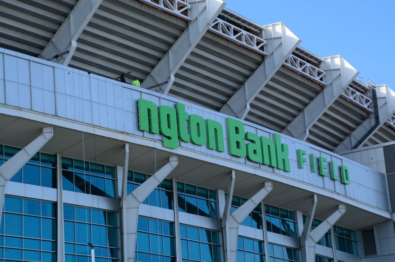 Workers stand above letters spelling out the name of Huntington Bank Field