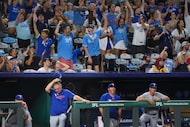 The Texas Rangers dugout and fans react after Kansas City Royals' Bobby Witt Jr. hit a...