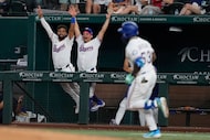 Texas Rangers' Ezequiel Duran, left, and Alejandro Osuna, center, lean on the rail...