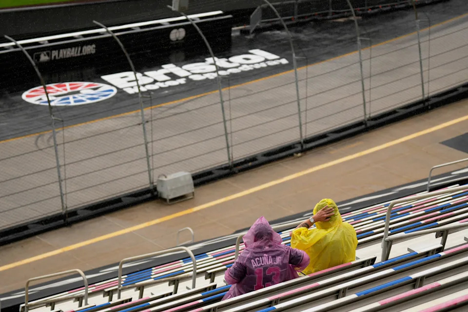 Fans wait in the rain before the MLB Speedway Classic baseball game between the Cincinnati Reds and the Atlanta Braves at Bristol Motor Speedway in Bristol, Tenn., Saturday, Aug. 2, 2025. (AP Photo/George Walker IV)