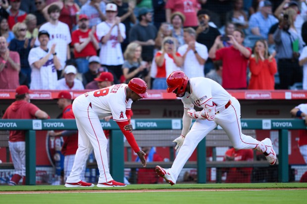 The Angels’ Jo Adell, right, celebrates with third base coach...
