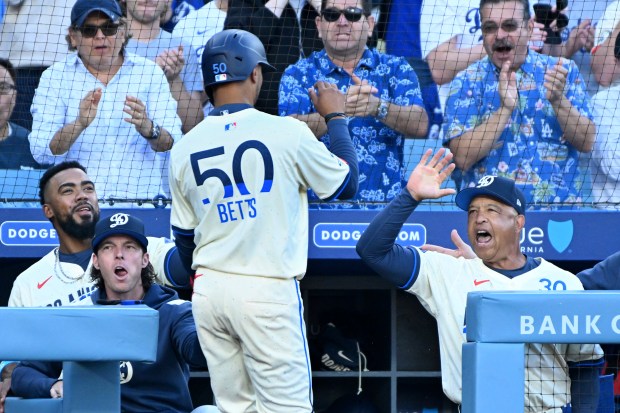 Dodgers manager Dave Roberts, right, congratulates Mookie Betts (50) after...