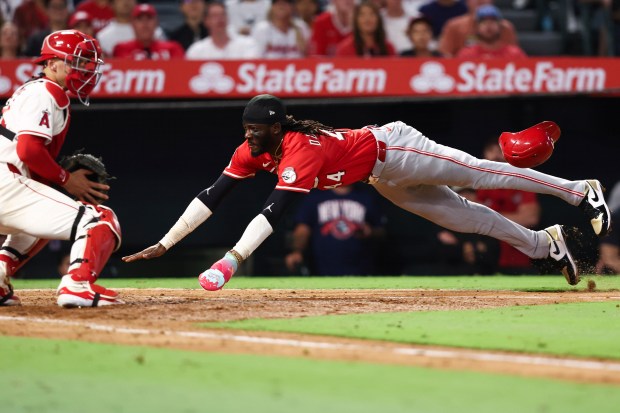 The Cincinnati Reds’ Elly De La Cruz, right, slides into...