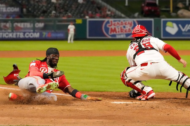 The Cincinnati Reds’ Elly De La Cruz, right, scores on...