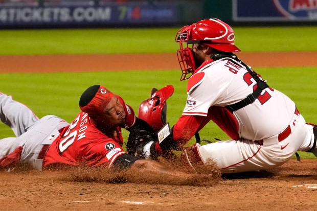 The Cincinnati Reds’ Will Benson, left, is tagged out by...
