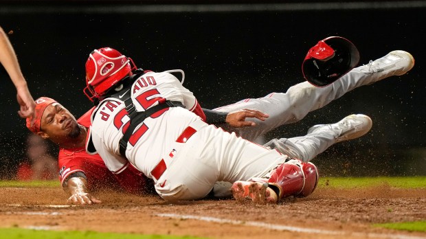 The Cincinnati Reds’ Will Benson, left, is tagged out by...