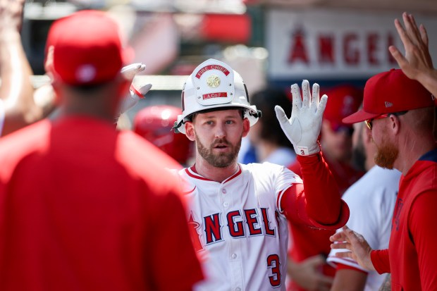 The Angels’ Taylor Ward celebrates with teammates in the dugout...