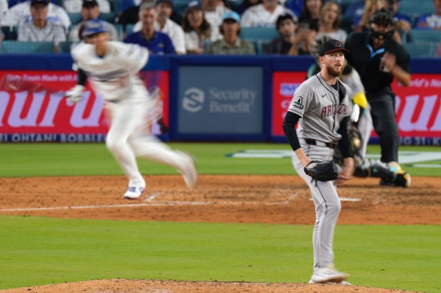 Dodgers star Shohei Ohtani, left, runs to first on a...