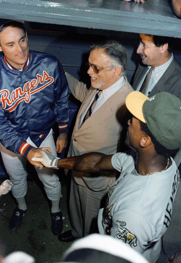 Oakland As Rickey Henderson, right, congratulates Texas Rangers pitcher Nolan Ryan, left, after their game, Tuesday, Aug. 23, 1989, Arlington, Tex. Henderson struck out in the fifth inning, giving Ryan his 5000th career strikeout. Commissioner of Baseball A. Bartlett Giamatti, center, and Rich Levin also congratulate Ryan. (AP Photo/IK)