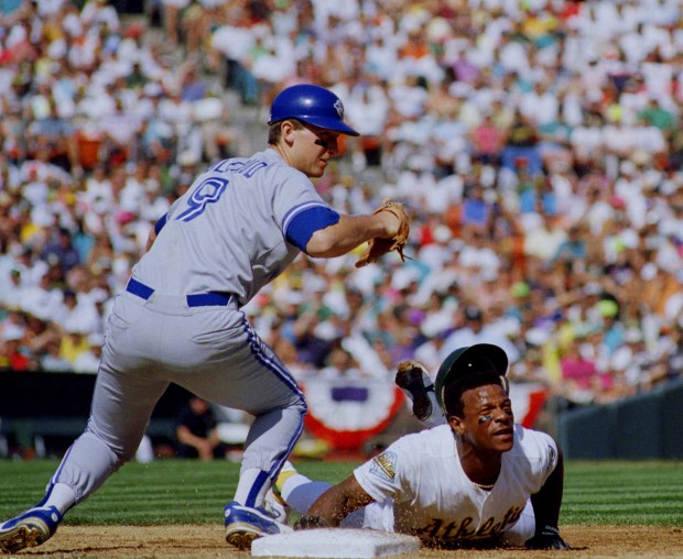 The Toronto Blue Jays' John Olerud looks for the ball over Oakland?s Rickey Henderson while trying to get to a wild pickoff throw from pitcher David Cone in the third inning of Game 5 of the American League Championship Series, Monday, Oct. 13, 1992 at Oakland Coliseum. Henderson made it to third base on the error and the A?s went on to beat the Jays 6-2. (AP Photo/Eric Risberg)