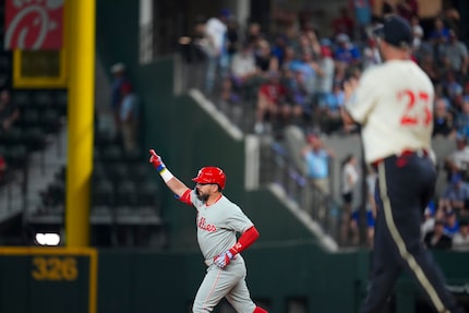 Philadelphia Phillies designated hitter Kyle Schwarber, left, gestures while running the...