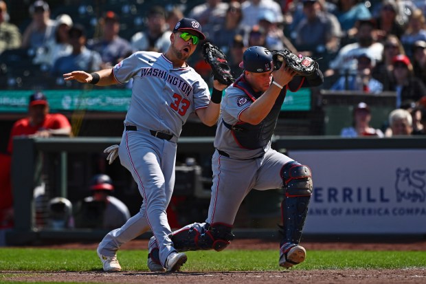 Washington Nationals’ Nathaniel Lowe (33) crashes into the catcher Riley...