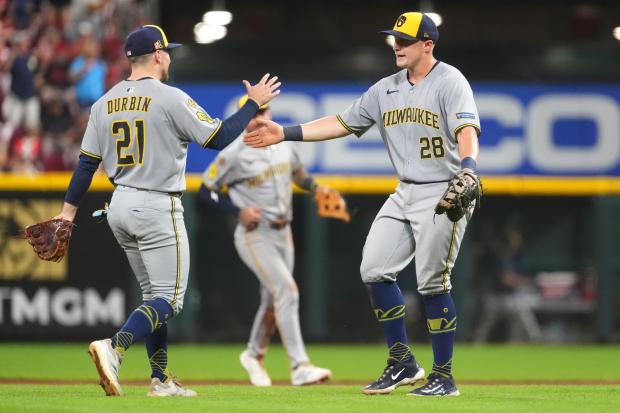 Milwaukee Brewers' Caleb Durbin, left, and Milwaukee Brewers' Andrew Vaughn, right, celebrate their win at the conclusion of the ninth inning of a baseball game against the Cincinnati Reds, Friday, Aug. 15, 2025, in Cincinnati. (AP Photo/Kareem Elgazzar)