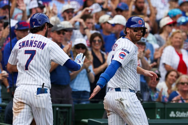Chicago Cubs catcher Carson Kelly (15) high-fives shortstop Dansby Swanson (7) after Swanson hit a sacrifice fly to get Kelly home and take the lead during the eighth inning against the Pittsburgh Pirates at Wrigley Field on Sunday, Aug. 17, 2025. (Eileen T. Meslar/Chicago Tribune)