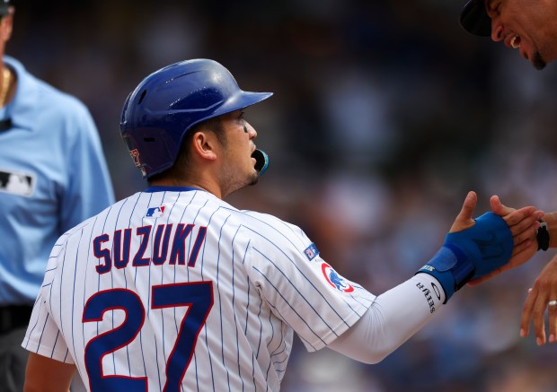 Chicago Cubs outfielder Seiya Suzuki (27) gets a high-five from Chicago Cubs third base coach Quintin Berry (0) after sliding in safely to third base on a single from outfielder Pete Crow-Armstrong (4) during the sixth inning against the Pittsburgh Pirates at Wrigley Field on Sunday, Aug. 17, 2025. (Eileen T. Meslar/Chicago Tribune)