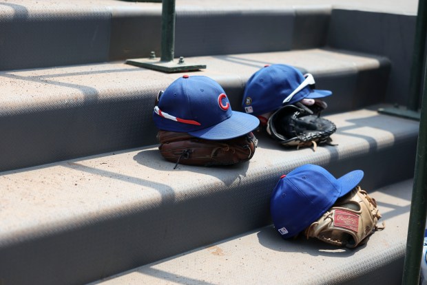 Chicago Cubs players prepare their hats and gloves in the dugout before facing the Cincinnati Reds on Wednesday, Aug. 6, 2025, at Wrigley Field. (Brian Cassella/Chicago Tribune)