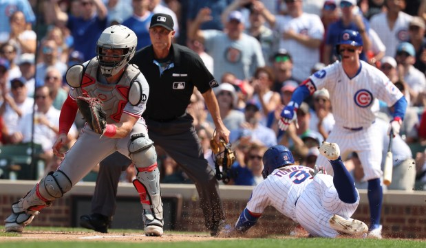 Chicago Cubs first baseman Justin Turner scores behind Cincinnati Reds catcher Tyler Stephenson in the seventh inning Wednesday, Aug. 6, 2025, at Wrigley Field. (Brian Cassella/Chicago Tribune)