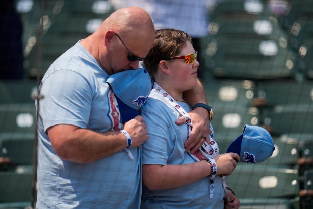 David Roberton, left, and his son Lex stand with their hats off as Cubs Hall of Famer Ryne Sandberg, who died from cancer this week, is honored before a game against the Orioles on Friday, Aug. 1, 2025, at Wrigley Field. (AP Photo/Erin Hooley)