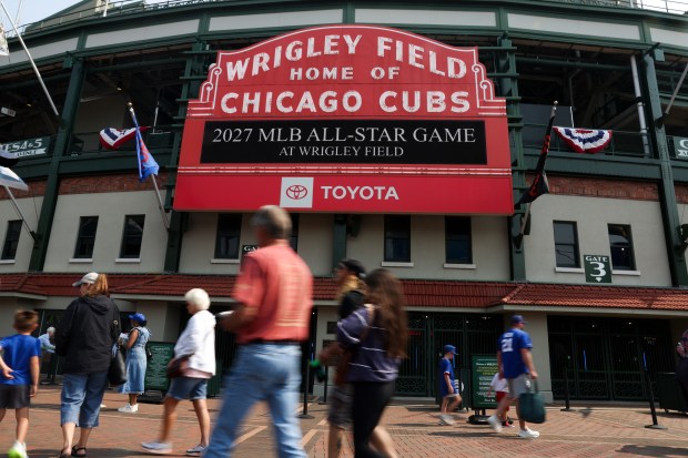 People walk in front of the marquee outside of Wrigley...