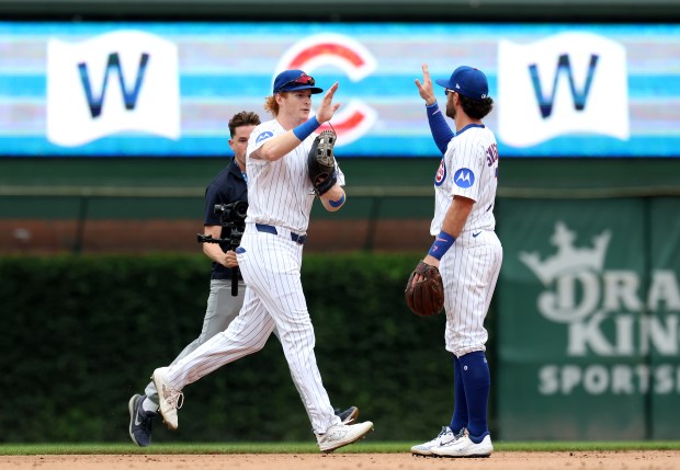 Chicago Cubs players Owen Caissie (left) and Dansby Swanson celebrate after their victory in Game 1 of a doubleheader against the Milwaukee Brewers at Wrigley Field in Chicago on Aug. 19, 2025. (Chris Sweda/Chicago Tribune)