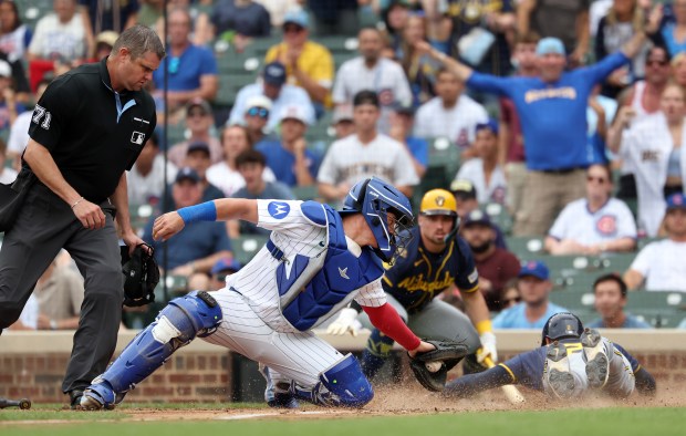 Chicago Cubs catcher Reese McGuire is unable to tag out Milwaukee Brewers second baseman Brice Turang at home plate in the sixth inning of Game 1 of a doubleheader against at Wrigley Field in Chicago on Aug. 19, 2025. (Chris Sweda/Chicago Tribune)