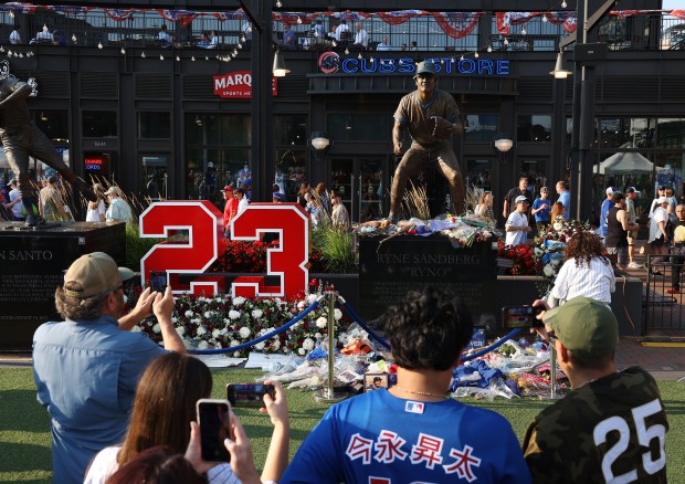 Fans flock to the Ryne Sandberg statue in Gallagher Way outside of Wrigley Field in Chicago before a game between the Cubs and the Cincinnati Reds at Wrigley Field in Chicago on Aug. 5, 2025. Sandberg died last week after a battle with cancer. (Chris Sweda/Chicago Tribune)