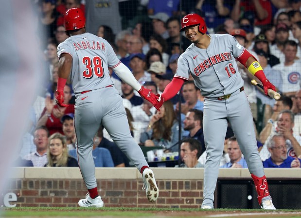 Cincinnati Reds designated hitter Miguel Andujar (38) is congratulated by teammate Noelvi Marte (16) after Andujar scored on a single by Spencer Steer in the fifth inning of a game against the Chicago Cubs at Wrigley Field in Chicago on Aug. 5, 2025. (Chris Sweda/Chicago Tribune)