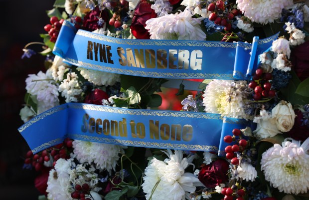 Flowers are seen among items honoring Cubs legend Ryne Sandberg at the base of his statue in Gallagher Way outside of Wrigley Field in Chicago before a game between the Cubs and the Cincinnati Reds at Wrigley Field in Chicago on Aug. 5, 2025. Sandberg died last week after a battle with cancer. (Chris Sweda/Chicago Tribune)