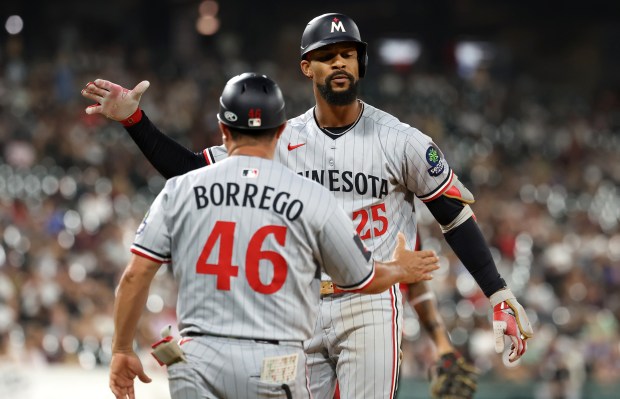 Minnesota Twins center fielder Byron Buxton (25) is congratulated by first base coach Ramon Borrego (46) after Buxton drove in a run on a single in the ninth inning of a game against the Chicago White Sox at Rate Field in Chicago on Aug. 22, 2025.  (Chris Sweda/Chicago Tribune)