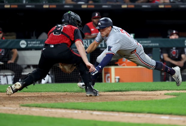 Minnesota Twins shortstop Brooks Lee sprints around to score in front of the tag of Chicago White Sox catcher Kyle Teel in the seventh inning of a game at Rate Field in Chicago on Aug. 22, 2025.  (Chris Sweda/Chicago Tribune)