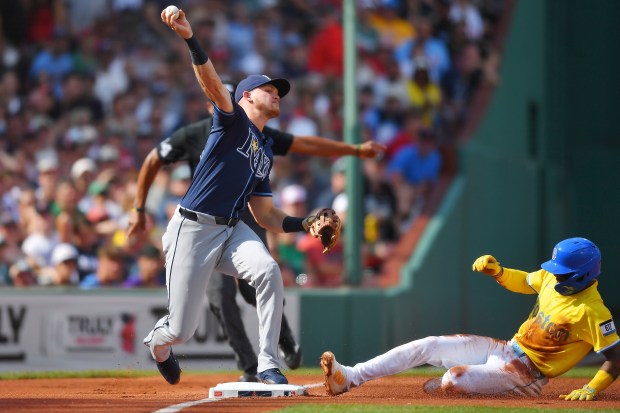 Boston Red Sox's Ceddanne Rafaela, right, slides out at third as Tampa Bay Rays third baseman Curtis Mead, left, throws to first to complete a double play in the first inning of a baseball game, Saturday, July 12, 2025, in Boston. (AP Photo/Steven Senne)