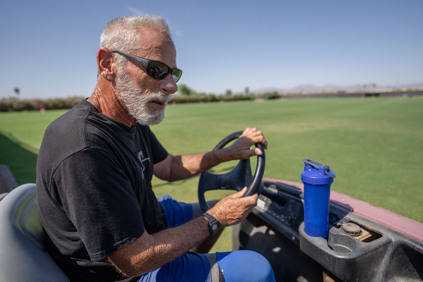 Rehab pitching coordinator Keith Comstock drives a golf cart at the Texas Rangers practice...