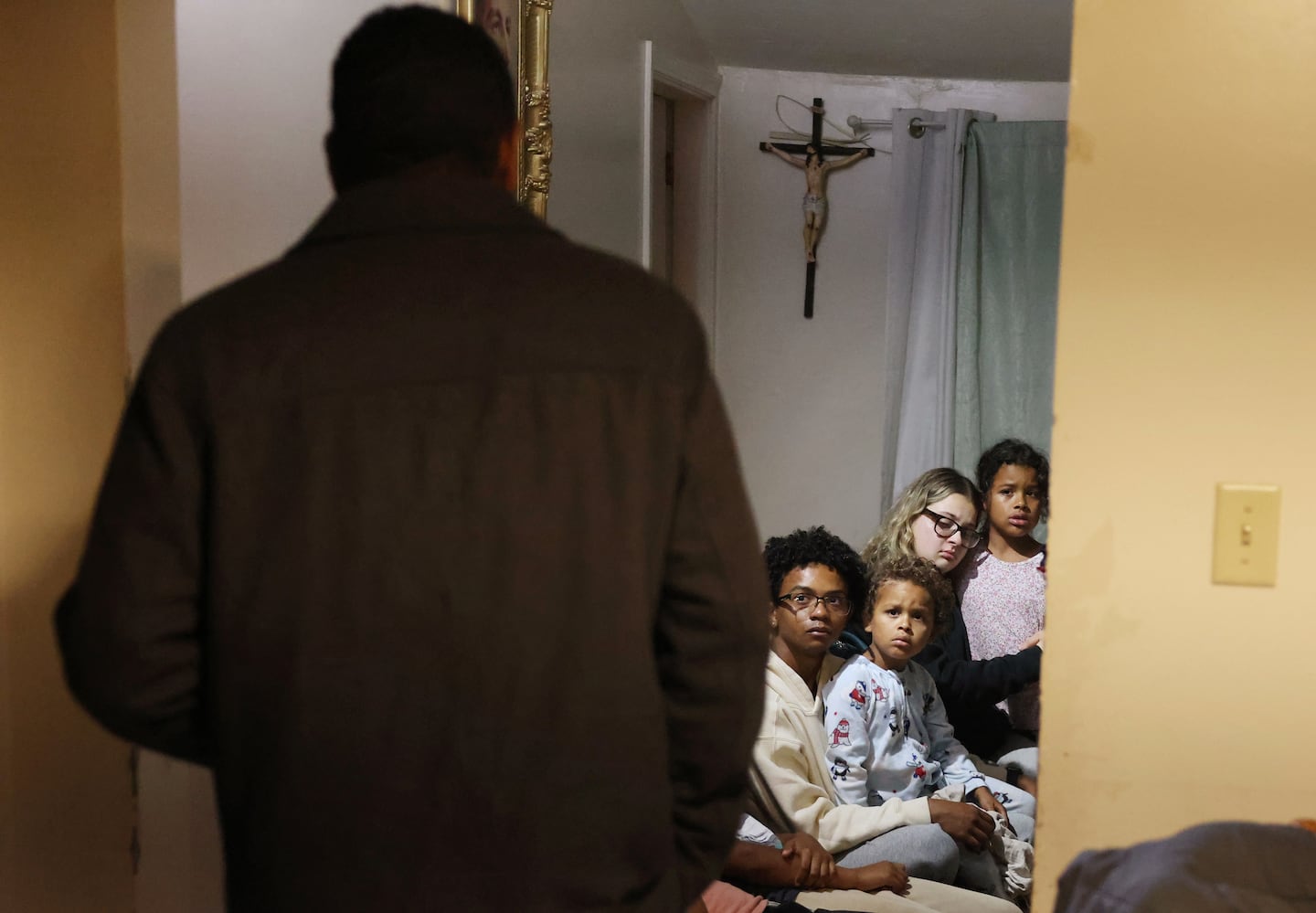 Frilei Brás lingered in the doorway of the kitchen as his daughters Sarah (right), 9, Clara (second from right), 19, and his son Rafael, 4, sat with his daughter’s boyfriend just before he was to leave the house and his family for the last time in Stoughton. Facing the possibility of arrest, the native of Brazil chose to self-deport.