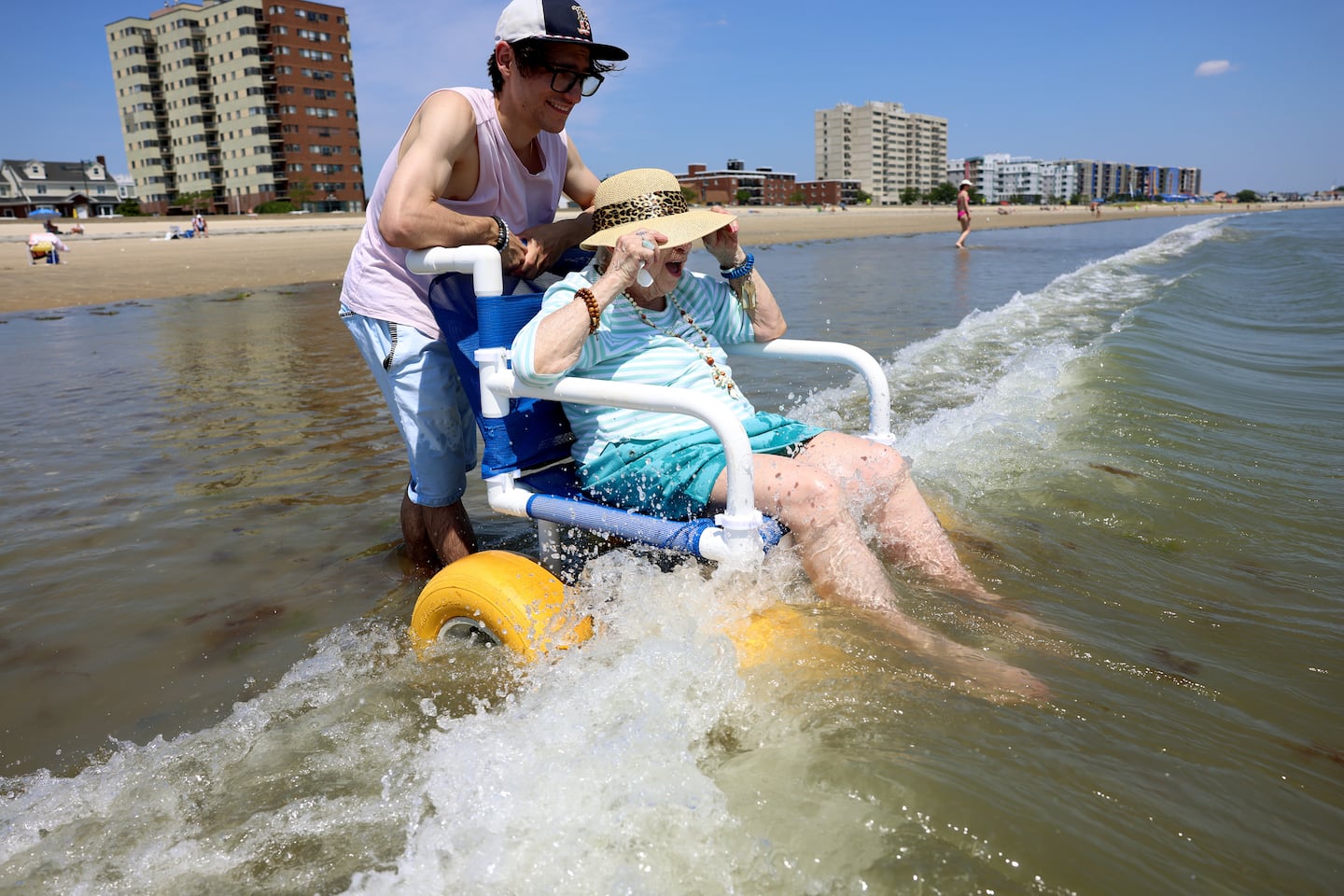 Mary Ciampolillo, a resident of Cohen Florence Levine Estates assisted living, held onto her hat on July 29 as Randy McCusker, an activities assistant, helped push her into the water at Revere Beach. It was another record-breaking day in Boston, with the temperature hitting 99 degrees.