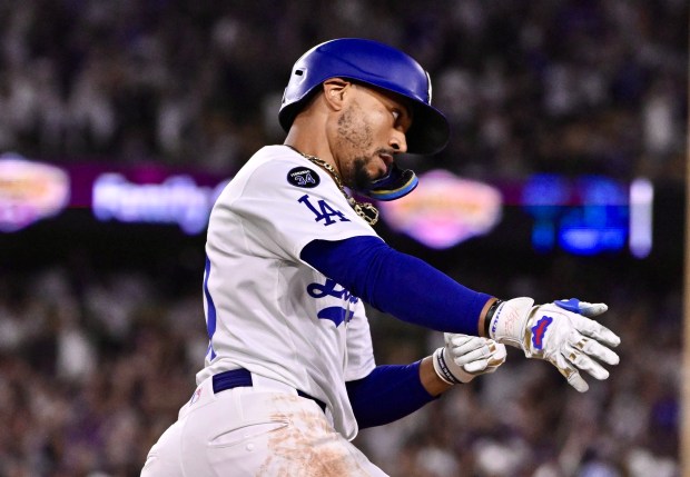 Mookie Betts #50 of the Dodgers rounds first after hitting...