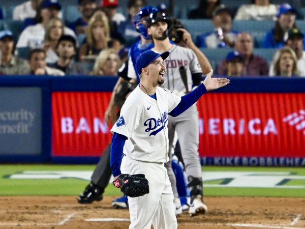 Dodgers starting pitcher Blake Snell, front, reacts as he watches...