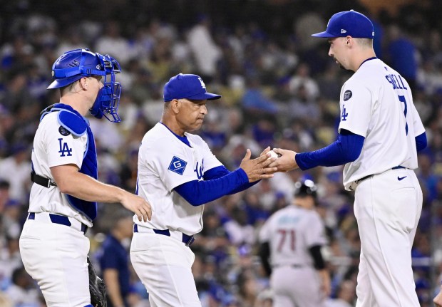 Dodgers manager Dave Roberts, center, takes the ball from starting...